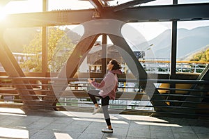 Willful young woman exercising on a steel girder walking bridge. Side view