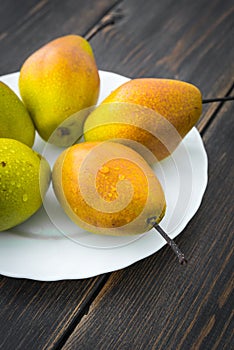 Williams pears of different ripeness in white circular plate