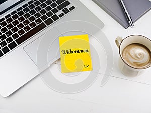 Willkommen or welcome with smiley face icon on desk