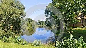 Willows, maples and alders grow on the grassy shore of the lake, and reeds and lilies grow in the water. On the far shore there ar photo