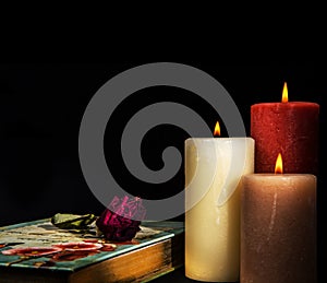 Wilted Faded red rose on book diary with three burning candles. Romantic Concept