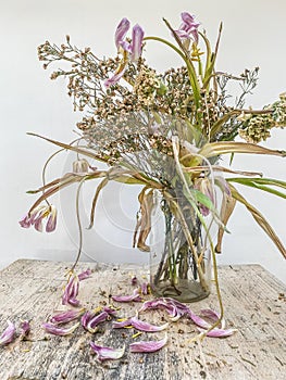 Wilted flowers bouquet in a clear glass vase