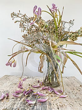 Wilted flowers bouquet in a clear glass vase photo