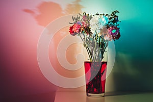 Wilted flowers in red water in colored light