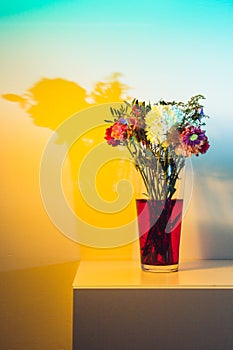 Wilted flowers in red water in colored light