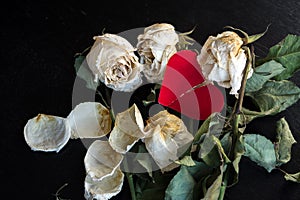 Wilted rose flowers and torn in half a paper heart, the concept of a broken heart, breakup