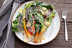 Wilted swiss chard salad with butter and garlic on rustic table