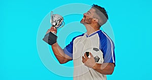 Win, football and face of a man with a trophy isolated on a blue background in studio. Happy, success and portrait of a