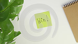 Win Top view write with a pen on a sticker. Put a colored piece of paper on your office desk and write a note with a