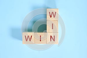 Win-win or win win in business concept. Wooden blocks crossword puzzle flat lay in blue background.