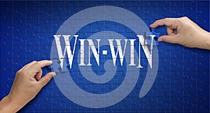Win win word on Jigsaw puzzle. Man hand holding a blue puzzle to
