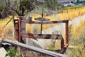 Winch of pair of rusty antique irrigation ditch gates against sky with tall grass in Heber City, Utah along the back side of the W