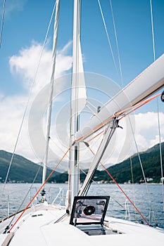 Winch of white sailing yacht with a red rope. Open glass hatch in the bow of the ship