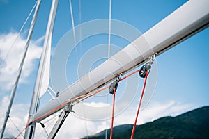 Winches with red ropes on a white mast of a sailing yacht against a bright blue sky