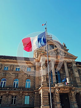 Wind blowing France flag on the mast against blue sky background in front of Palais du Rhin, Place de la Republique, Strasbourg photo