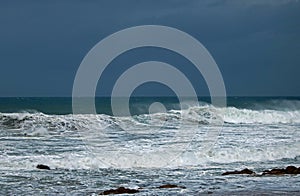 WIND BLOWING SPRAY FROM THE SURF ON A WAVE IN THE OCEAN.