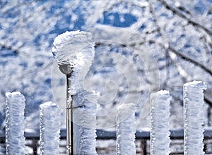 Wind-blown frost on fence lamp and fence poles