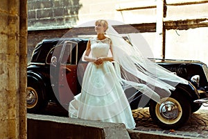 Wind blows bride's veil away while she steps ou of a retro car