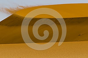 Wind on the crest of a of red dune in the Namib Desert, Sossusvlei, Namibia