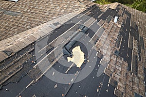 Wind damaged house roof with missing asphalt shingles after hurricane Ian in Florida. Repair of home rooftop concept