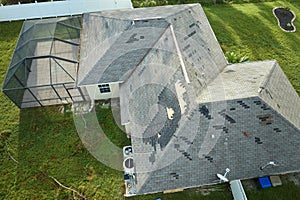 Wind damaged house roof with missing asphalt shingles after hurricane Ian in Florida. Repair of home rooftop concept