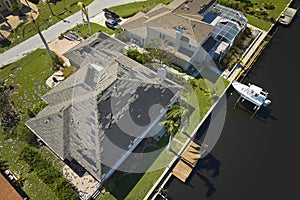 Wind damaged house roof with missing asphalt shingles after hurricane Ian in Florida. Repair of home rooftop concept