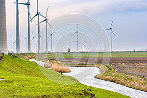 Wind electricity with water channel and old wind mill in background between new technology on the north of Netherlands near Eemsha