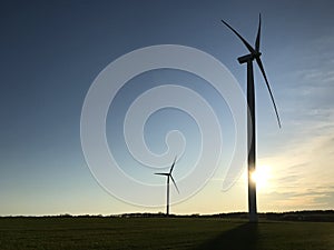 Windmill or wind turbine with the setting sun behind and copyspace photo