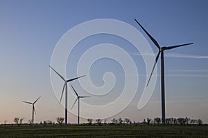 Wind energy turbines on sunset sky background, Energy generator nature friendly. Yellow colza field.