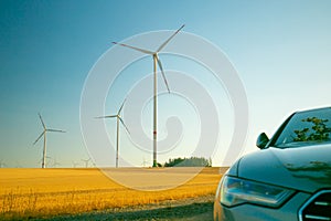 Wind energy. Wind generators and electric car in the field .Alternative energy for cars.Refueling the car with renewable