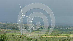 Wind farm in green field, wind turbines spinning, alternative energy sources