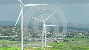 Wind farm in rural area. Wind turbines in green field rotating under stormy sky
