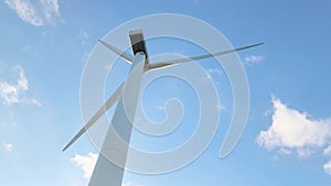 Wind generator against a blue sky with clouds. Rotation of white wind turbine blades