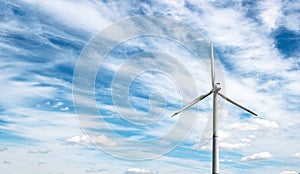 Wind generator of electricity from three blades against the background of clouds and blue sky