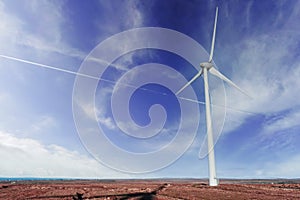 Wind generator in a field. Blue cloudy sky in the background. Orange warm color grass. Modern technology in natural environment.