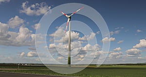 Wind generator in the field. Rotation of wind turbine blades against the sky. Wind turbine in a green field against a