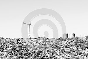 Wind generator and two water tanks on a hill. Monochrome