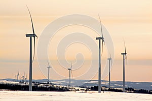wind generator under sunset sky, snow landscape .Powerplant electric turbine. Clean energy and eco energy concept.