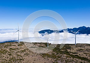 Wind generators with over clouds background and blue sky on clear summer day on the mountain range aerial view, Madeira,Portugal.
