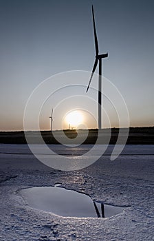 Wind generators reflected in a puddle of water on the background of the sky without clouds at sunset near the Lemurian photo