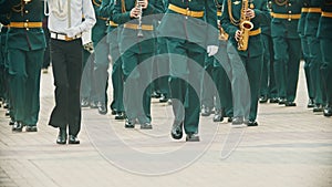 A wind instrument parade - military musicians in green costumes marching on the street holding musical instruments