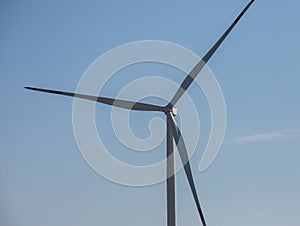 wind mill or also wind-turbine on wind farm in rotation to generate electricity energy on outdoor with sun and blue sky