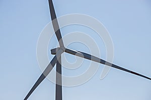 wind mill or also wind-turbine on wind farm in rotation to generate electricity energy on outdoor with sun and blue sky