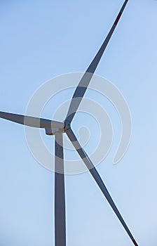 wind mill or also wind-turbine on wind farm in rotation to generate electricity energy on outdoor with sun and blue sky