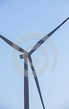 wind mill or also wind-turbine on wind farm in rotation to generate electricity energy on outdoor with sun and blue sky