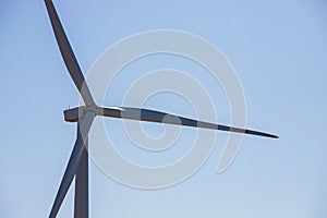 wind mill or also wind-turbine on wind farm in rotation to generate electricity energy on outdoor with sun and blue sky