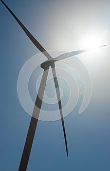 wind mill or also wind-turbine on wind farm in rotation to generate electricity energy on outdoor with sun and blue sky