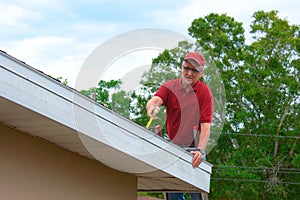 Wind mitigation inspection inspector on a ladder doing inspection on new roof to generate a risk rating