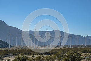 Wind park with windmills or wind turbines against mountains and blue sky