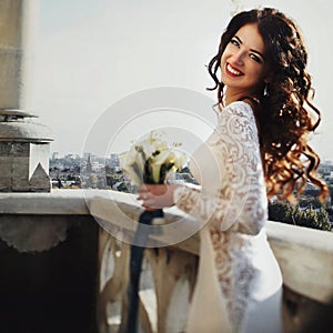 Wind plays with bride's curlu hair on the balcony